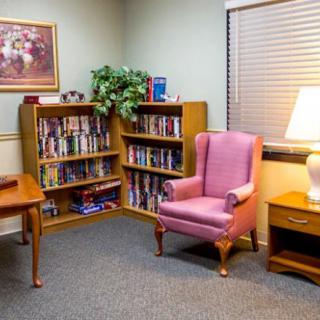 Cozy reading nook with a bookshelf, armchair, and lamp.