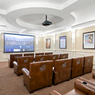 A cozy home theater with rows of plush leather seating, a large projection screen, and elegant interior lighting.