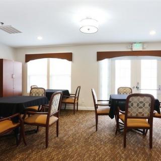 A well-lit dining area with round tables and upholstered chairs.
