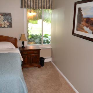 A cozy bedroom with a single bed, nightstand, and window view.