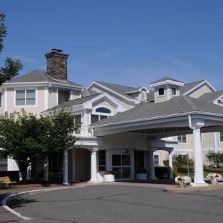A residential building with a covered entrance and surrounding trees under a clear blue sky.
