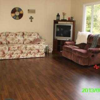 Cozy living room with a floral couch and armchair, featuring a television and wooden flooring.