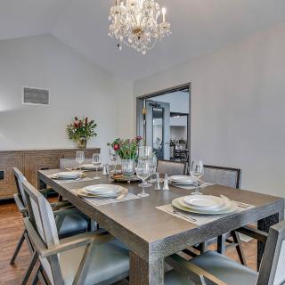 A modern dining room with a stylish table setting and a chandelier.