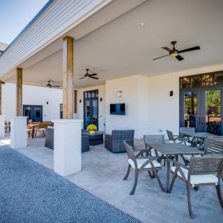 A modern outdoor patio with comfortable seating and dining area, featuring ceiling fans for added comfort.