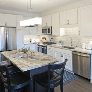 A modern kitchen with an island, featuring stainless steel appliances and white cabinets.