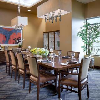 A well-appointed dining room with a long wooden table set for a formal meal, featuring elegant chairs, chandeliers, and contemporary artwork.