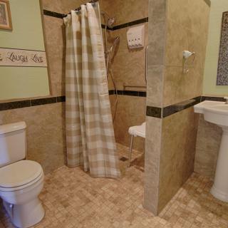 A modern bathroom featuring a shower with a checked curtain, toilet, and pedestal sink.