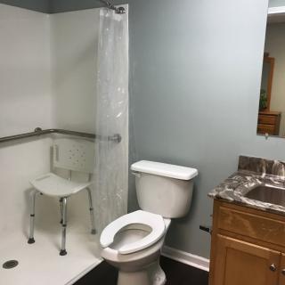 An accessible bathroom with a shower, toilet, and sink.