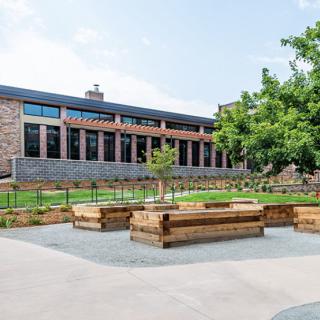 A modern building with a courtyard featuring wooden benches and greenery.
