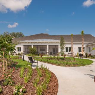 A modern building with a landscaped garden and winding pathway under a blue sky.
