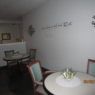 A cozy seating area with tables and chairs, adorned with wall decorations and plant centerpieces.