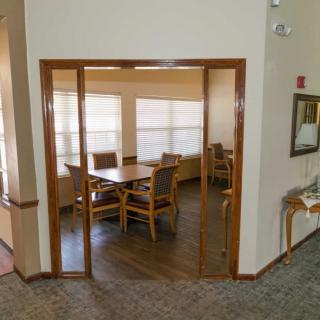 A cozy dining area with a wooden table and chairs surrounded by large windows.