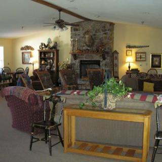 A cozy living room with a stone fireplace and various furnishings.
