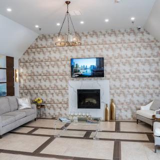 A modern living room featuring a stylish fireplace, decorative wall, and a large television.