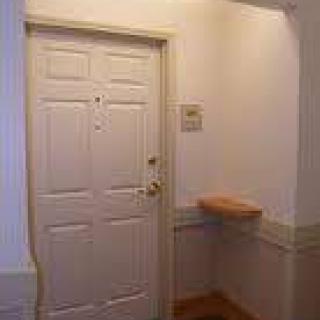 An interior view of a hallway with a closed door and a small shelf.