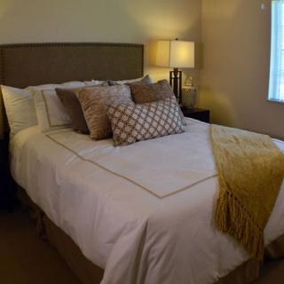 A cozy bedroom with a neatly made bed, accent pillows, and a warm blanket.