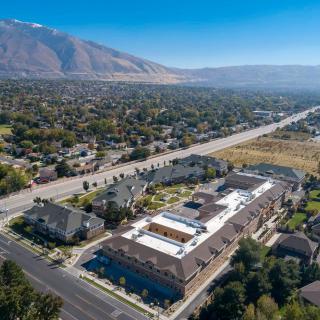 Aerial view of a suburban neighborhood with buildings and a road, set against a backdrop of mountains.