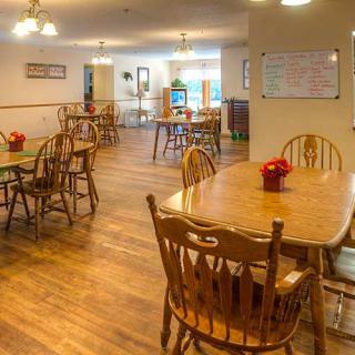 A cozy dining area with wooden tables and chairs, warmly lit and inviting.