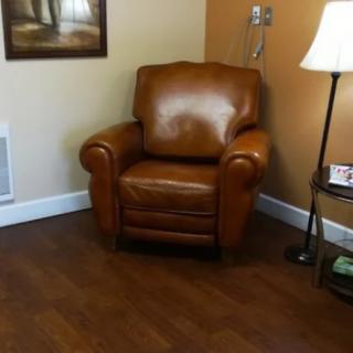 A cozy living room corner with a leather chair and a standing lamp.