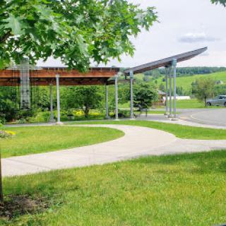 A modern architectural structure set in a lush green landscape, featuring a curved pathway.