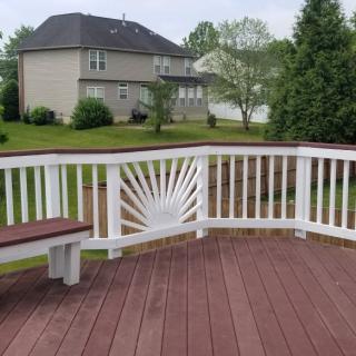 A wooden deck with white railings overlooks a suburban backyard.