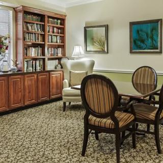 A cozy library corner with bookshelves, an armchair, and a small table set.