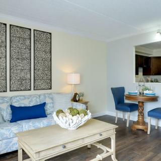 A cozy living room featuring a comfortable sofa, decorative artwork, and an adjoining dining area with blue chairs.
