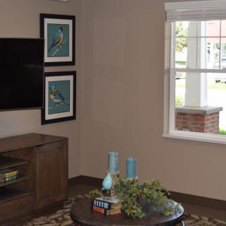 A cozy living room featuring a wall-mounted TV, two artworks, and a coffee table with decorative items.