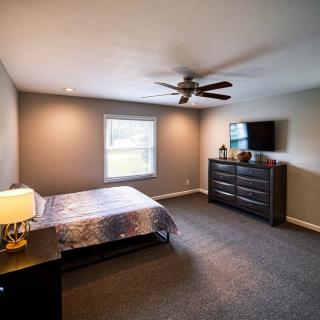 A spacious bedroom with modern furnishings, including a bed, dresser, and TV.