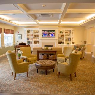 A cozy living room with elegant furniture and a built-in bookshelf, featuring a central seating area around a television.