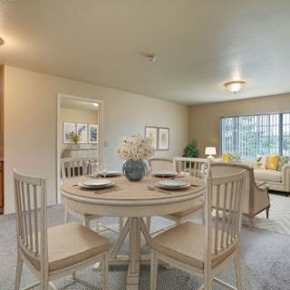 A cozy dining area featuring a round table with elegant chairs, surrounded by a warm and inviting living space.