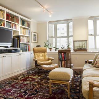 A cozy living room featuring a large bookshelf, television, and comfortable armchair with footstool.