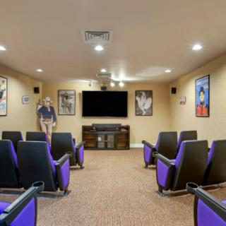 A cozy home theater room with purple seating and movie posters on the walls.