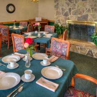 A cozy dining area set for a meal, featuring elegant table settings and a warm fireplace.