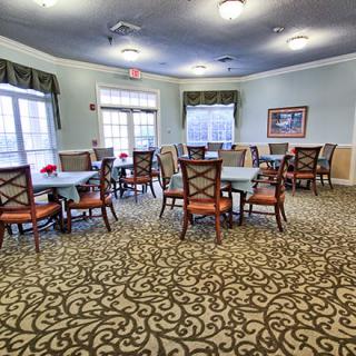 A well-lit dining area with elegant carpeting and neatly arranged tables and chairs.