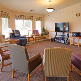 A cozy community living room with comfortable chairs arranged around a television.