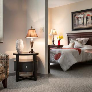 A cozy bedroom with a neatly made bed, warm lighting from table lamps, and tasteful decor.