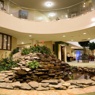 A spacious atrium with a decorative stone water feature and lush plants.