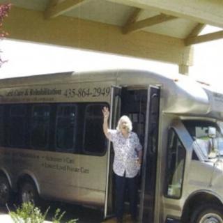 A person standing at the entrance of a bus parked under a structure.
