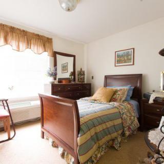 A cozy, traditionally furnished bedroom with a wooden bed and matching dresser.