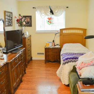 A cozy bedroom with a single bed, television, and wooden furniture.