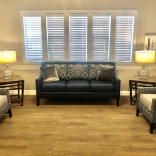 A cozy living room with a dark sofa, two armchairs, and soft lighting from lamps on side tables.