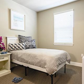A neatly arranged bedroom with a single bed, a nightstand, and a window.