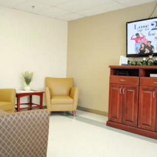 A comfortable waiting room with seating areas and a television.