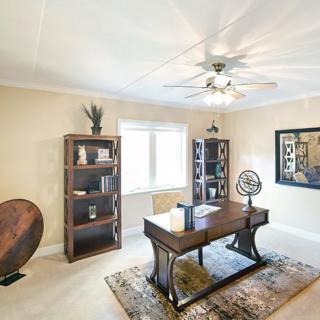 A well-lit home office with a desk, bookshelves, and decor.