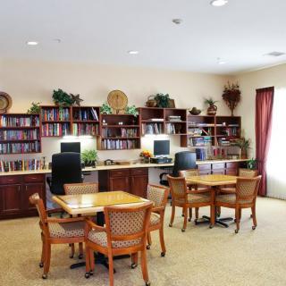 A quiet library with tables, chairs, computers, and bookshelves.