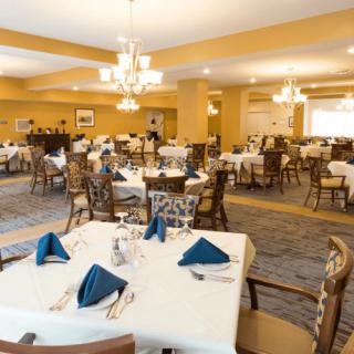 A spacious restaurant dining area with elegantly set tables and chandeliers.