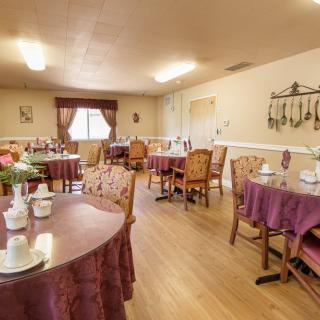 A cozy dining area with neatly arranged tables and chairs, ambient lighting, and elegant decor.