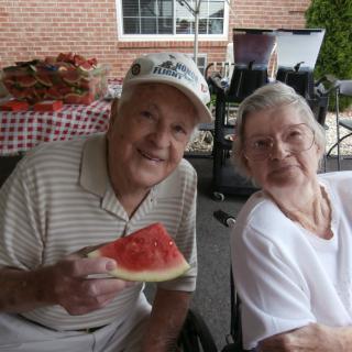 An elderly couple enjoying a slice of watermelon together outdoors.