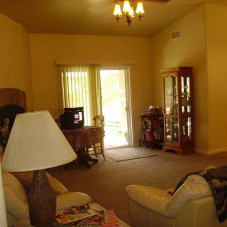 A cozy living room with a sofa, lamp, television, and a cabinet near the window.